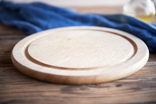 Round and empty wooden pizza board on wooden background
