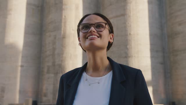 Portrait of young multiracial woman in businesswear smiling next to building