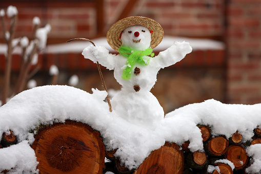 Woman makes a snowman in a city park during a snowfall.