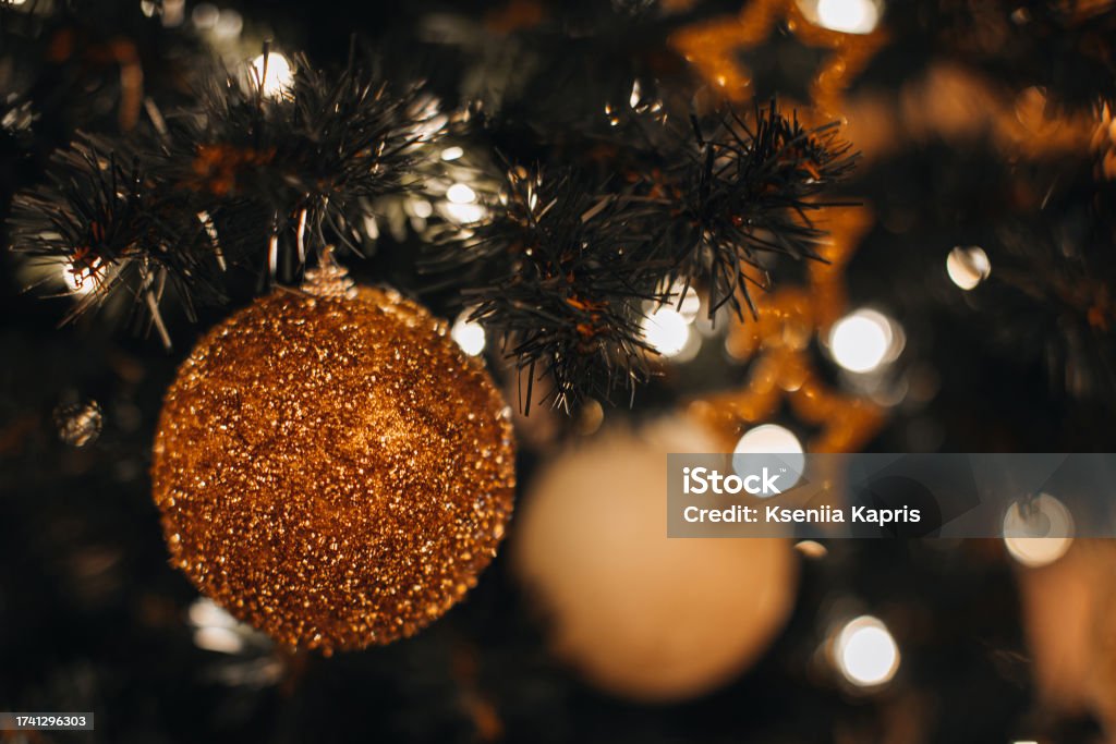 Details of Christmas ball with golden glitter hanging on the Christmas tree branches. Winter holiday fairy garlands illumination Abstract Stock Photo