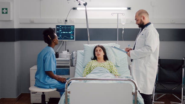istock Front view of sick woman lying on bed while afro-american nurse analyzing x-ray bones 1741311288