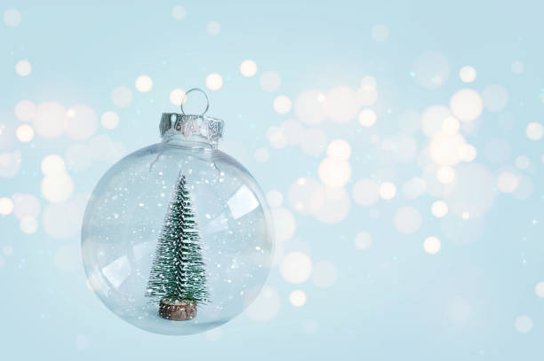 istock Glass snow ornament with Christmas tree on blue soft Christmas background 1741319837