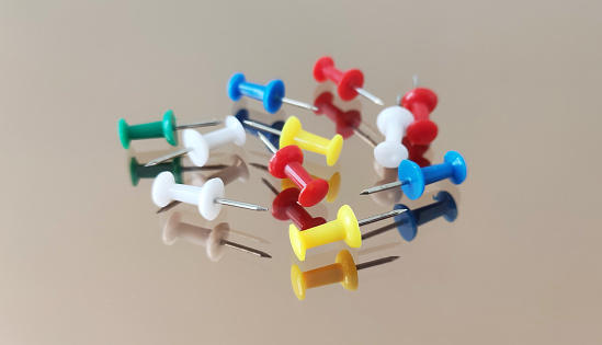 Colorful thumbtacks. Set of push pins with reflection on table.