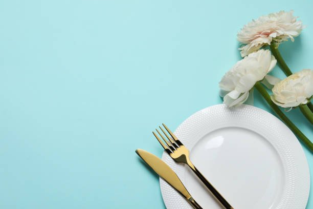 istock Stylish table setting with cutlery and flowers on light blue background, flat lay. Space for text 1741334441