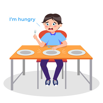 istock Vector illustration of a cute hungry boy. Cartoon scene of a boy sitting at a table with plates and holding a fork and spoon in his hands waiting for food isolated on white background. 1741376185