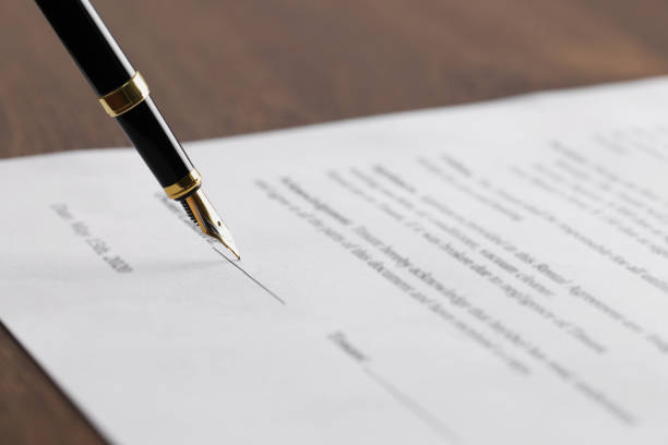 istock Writing on document with fountain pen at wooden table, closeup. Notary contract 1741385977
