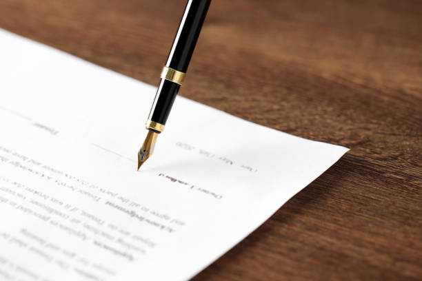 istock Writing on document with fountain pen at wooden table, closeup. Notary contract 1741386521