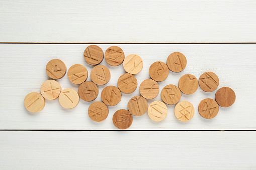 Runes with different symbols on white wooden table, flat lay
