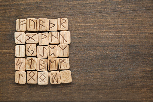 Runes with different symbols on wooden table, top view. Space for text