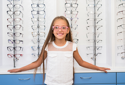 Little girl with a glasses standing in the optical store