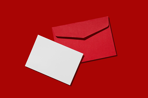 Blank white card with kraft red paper envelope on red background template mockup. Christmas concept.