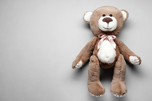 Cute teddy bear on grey background, top view. Space for text