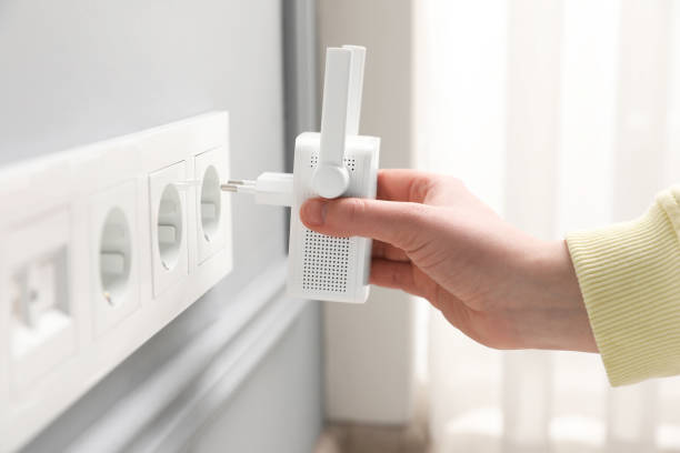 istock Woman inserting wireless Wi-Fi repeater into power socket indoors, closeup 1741406268
