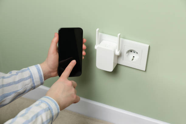 istock Woman using smartphone for wireless Wi-Fi repeater indoors, closeup 1741406598