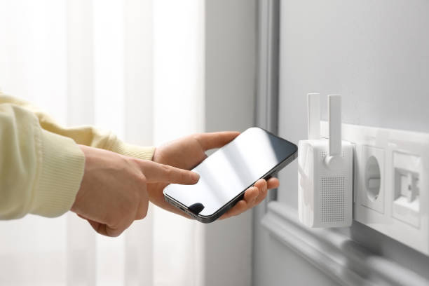 Woman using smartphone for wireless Wi-Fi repeater indoors, closeup