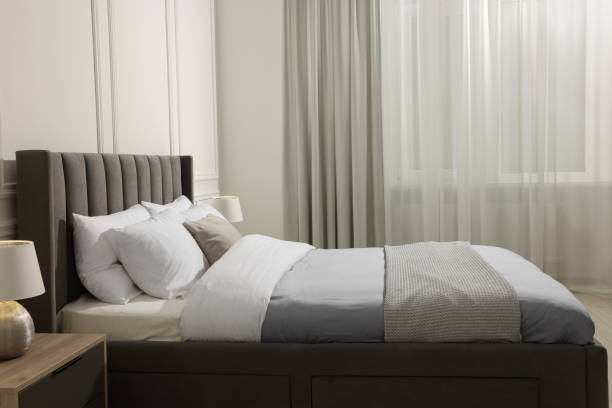 istock Comfortable bed near bedside table with lamp at home. Interior design 1741408566