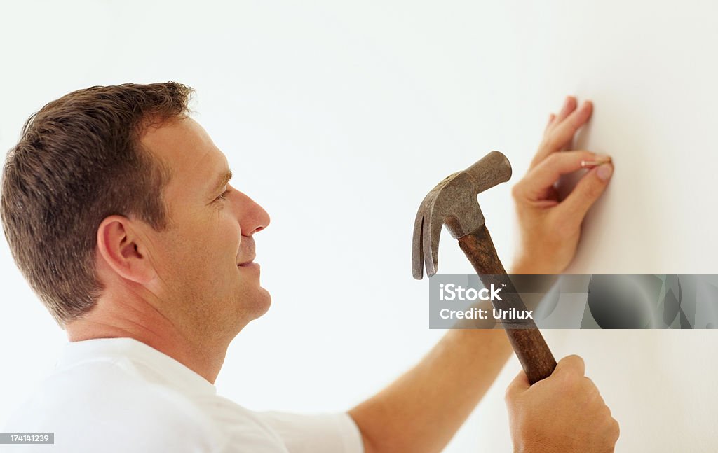 Smiling Mature Man Hammering A Nail Into A Wall Stock Photo - Download  Image Now - Hammer, Nail - Work Tool, Men - iStock