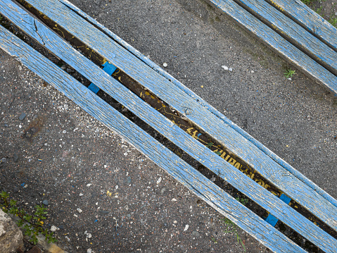 Old blue abandoned weathered wooden seats at the stadium top view, diagonal composition.