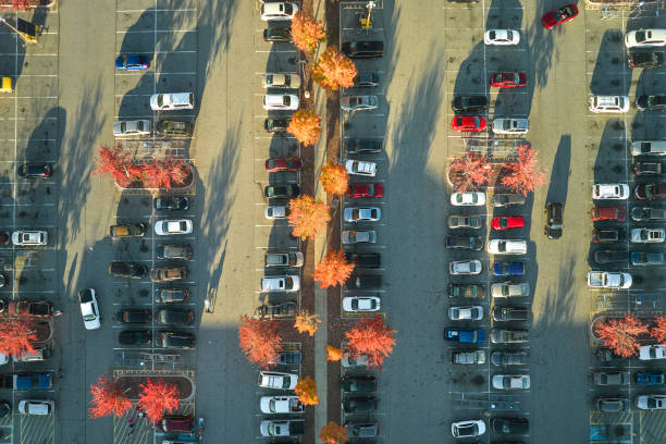 widok z góry na wiele zaparkowanych samochodów na parkingu z liniami i oznaczeniami miejsc parkingowych i kierunków. miejsce dla pojazdów przed centrum handlowym - strip mall shopping mall road street zdjęcia i obrazy z banku zdjęć