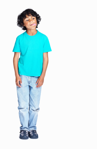 Serious Blonde Preteen Boy Wearing Green Shirt Posing Looking At Camera Standing Over Gray Studio Background. Kids Style And Fashion Concept. Front View