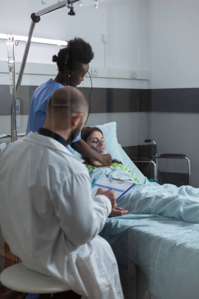 istock Doctor during morning rounds checking clipboard with patient records while nurse is putting oxygen mask 1741427443