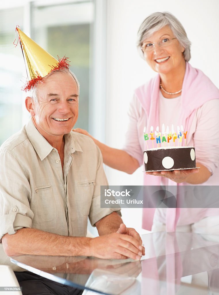 Senior woman celebrating husband's birthday with a cake  Adult Stock Photo