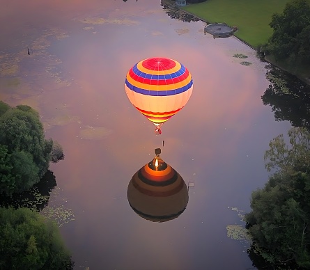 One big red ballon in the morning sunrise light over temples and lush green rainforest and rice fields agricultural fields