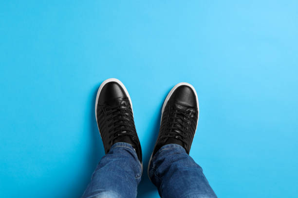 istock Man in stylish sneakers standing on light blue background, top view 1741436063
