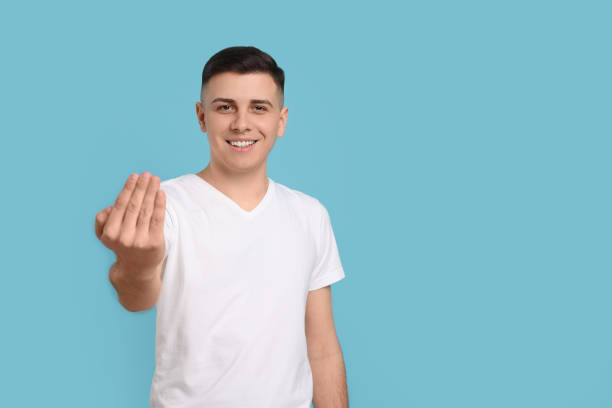 istock Handsome man inviting to come in against light blue background. Space for text 1741436571