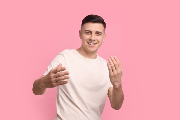 istock Handsome man inviting to come in against pink background 1741436621