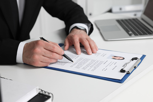 Human resources manager reading applicant's resume at table in office, closeup