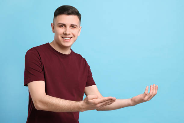 istock Handsome man inviting to come in against light blue background. Space for text 1741437736