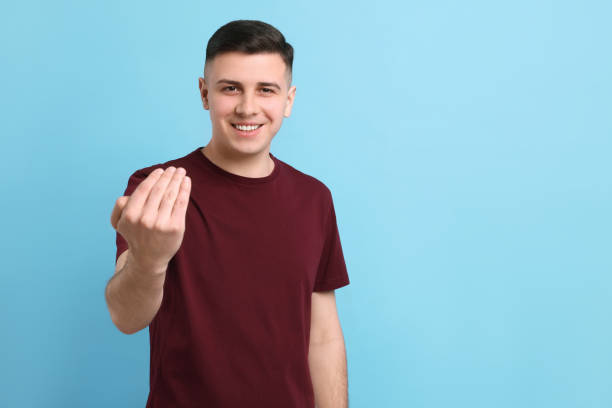 Handsome man inviting to come in against light blue background. Space for text