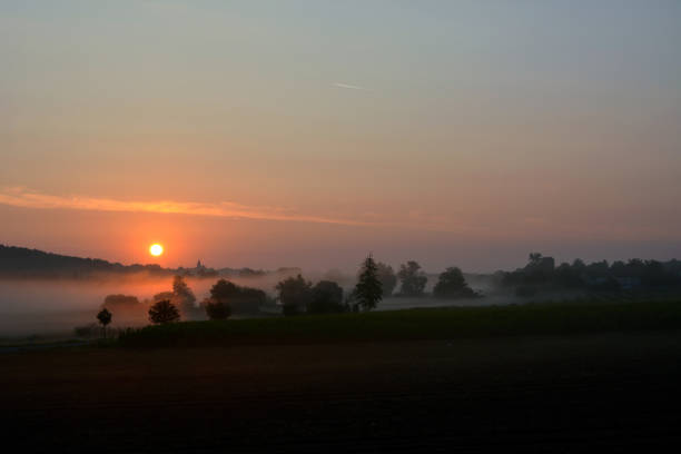 istock A fog creeps over the evening meadows, over which the bright sun sets 1741437774