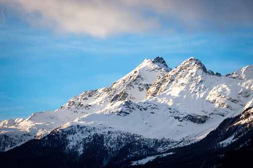 Scenic view of snow covered Cima Redasco (left)and Monte Zandila (right) mountains seen from Bormio, Italy in winter against blue sky