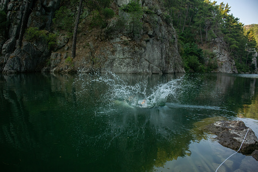 A swimmer jumping into a lake and splashing the water. Karacaoren dam lake.