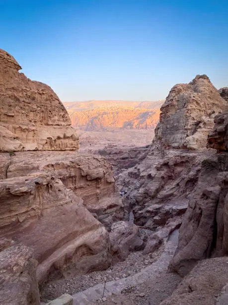 Scenic view along Ad-Deir Trail Monastery Route in the historic and archaeological city of Petra, Jordan with Royal Tombs and houses of Wadi Musa in the background at sunset