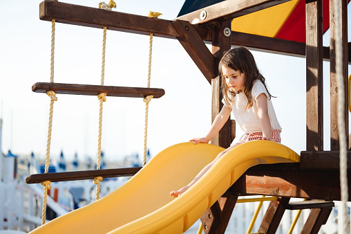 little girl sliding from an yellow slide.
