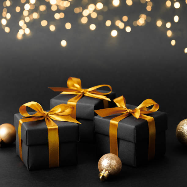 istock Black gift box with golden ribbon bow on black background 1741527551