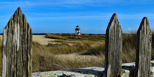 Brant Point Lighthouse sits off in the distance behind a dilapidated beach fence