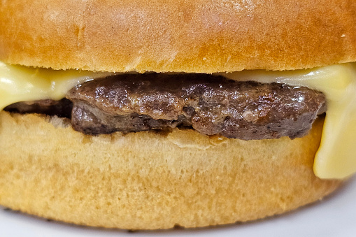 Juicy burger with appetizing grill marks on a silver spatula over a flaming charcoal barbecue grill