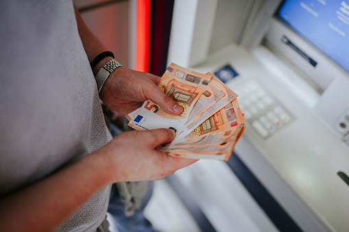 ATM and cash money. Euros withdrawal from an ATM machine, closeup view