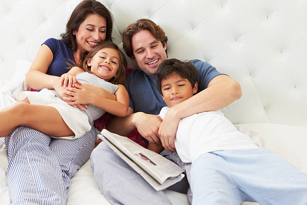 família relaxante na cama com café e jornal - reading newspaper 30s adult imagens e fotografias de stock