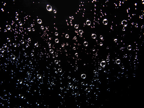 Many tiny soap bubbles in different colors on black background