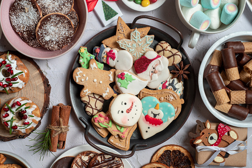 Christmas gingerbread cookies in a metal bowl on a table full of Christmas colorful sweets