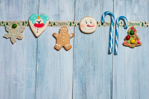 Homemade gingerbread’s and lollipops with Christmas decoration on a blue background with copy space