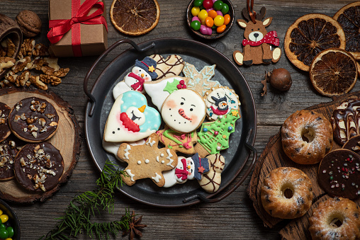 Christmas gingerbread’s, cakes, biscuits, chocolate, fruit on a wooden table with holiday decorations. Top view