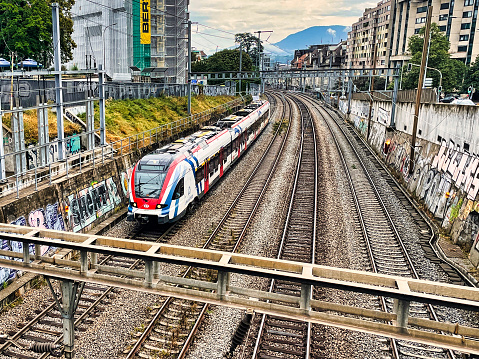 Geneva, Switzerland - September 15 2021: an urban view of a train on tracks leading into the city and connecting it to the national network