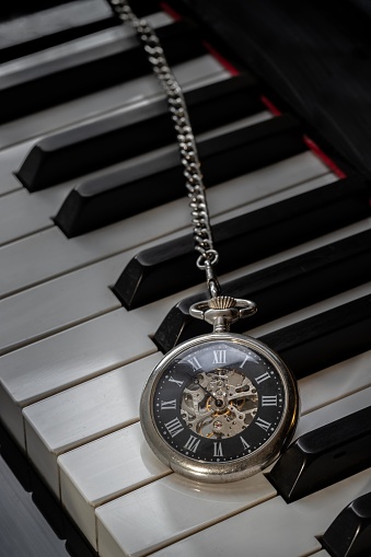 Antique pocket watch on piano keyboard. Time for music conceptual. Space for text, Selective focus.