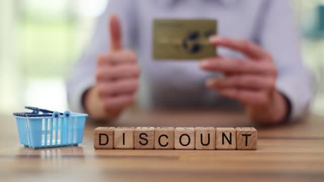 Word Discount and shopping basket against woman holding card